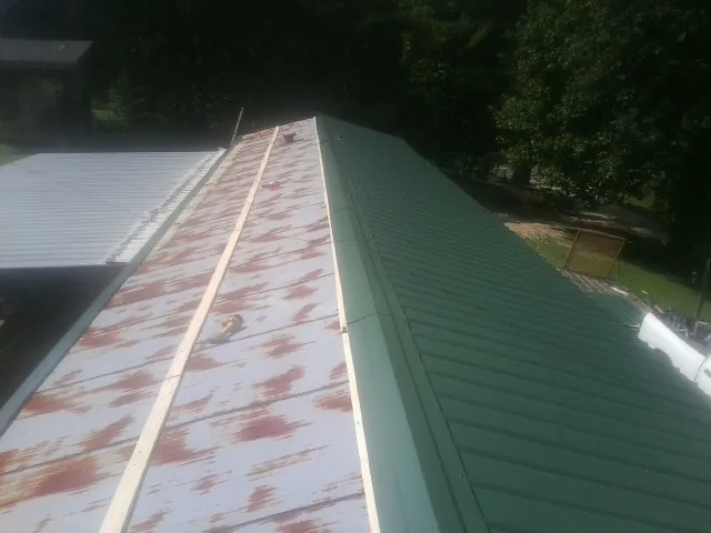 Old rusted panels beside newly installed green metal roofing — Wind Damage Roof Repair by Roofing Brothers in Bear