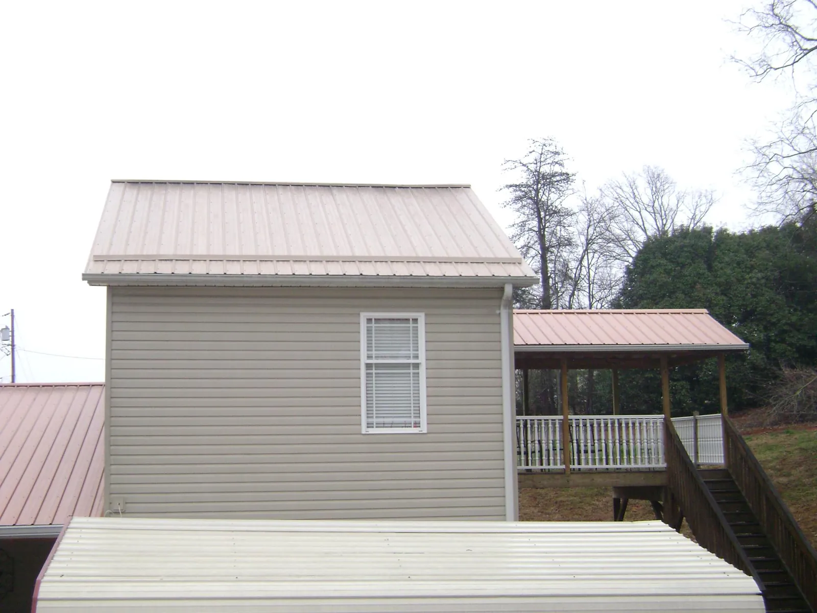 Tan metal roofs on a two story addition and attached porch, from a Roof Replacement job in Bear